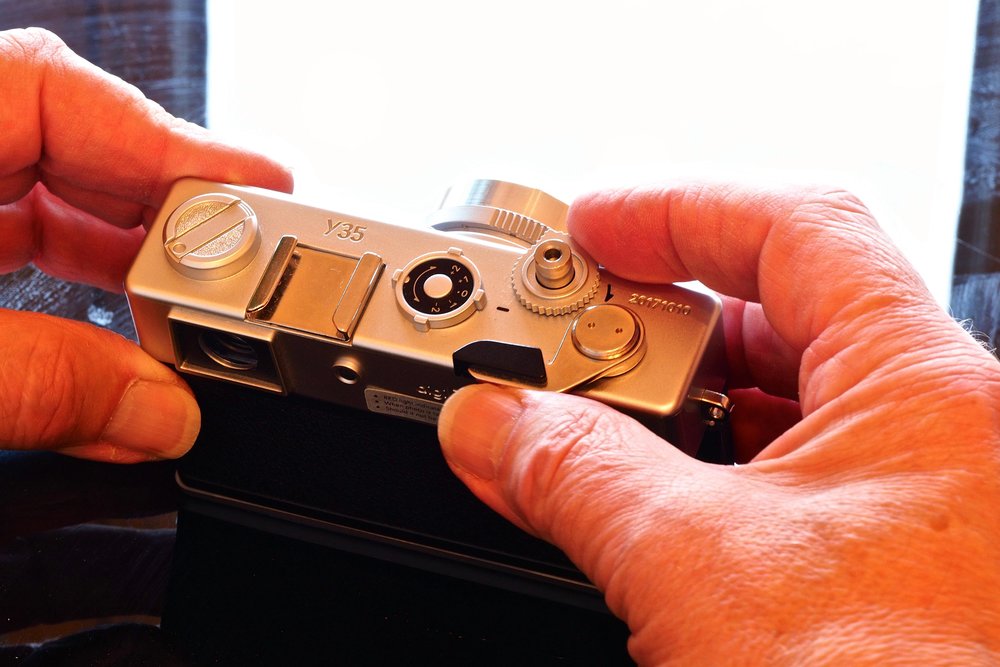 Plastic ‘Yashica’ Y35 14 megapixel camera with manual ‘wind-on’ shutter-interlock lever. Fixed focus, fixed aperture, auto-only shutter speeds, optical viewfinder, under- & over-exposure adjustment (by guesswork) lever on top, no screen.